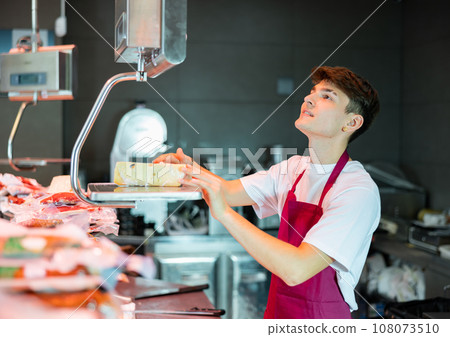 Young man weighing cheese at counter 108073510