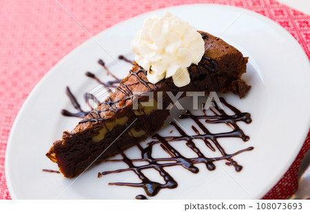 Tasty brownie cake served with butter cream and dark chocolate at plate 108073693