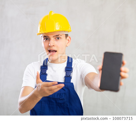 Surprised young guy posing in uniform with phone in his hand Surprised young guy posing in uniform with phone in his hand 108073715