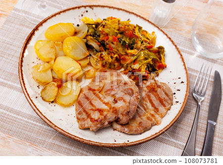 Roasted pork steak with baked potatoes and stewed cabbage Roasted pork steak with baked potatoes and stewed cabbage 108073781
