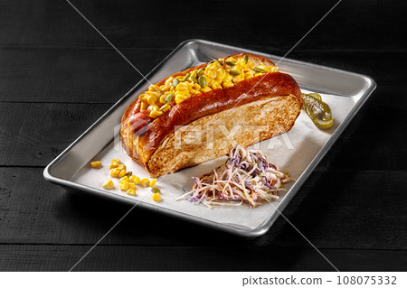 Hot dog in toasted bread with smoked sausage, cheese, corn, pickles and shredded cabbage 108075332