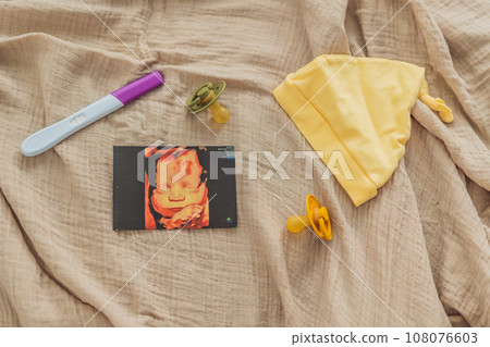 A composition of essential pregnancy attributes: a positive pregnancy test, ultrasound image, tiny pacifier, and a soft baby's cap, embodying the journey to motherhood A composition of essential pregnancy attributes: a positive pregnancy test, ultrasound image, tiny pacifier, and a soft baby's cap, embodying the journey to motherhood 108076603