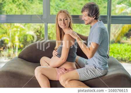 health, pregnancy and happy people concept - husband giving his wife back massage at home 108076615