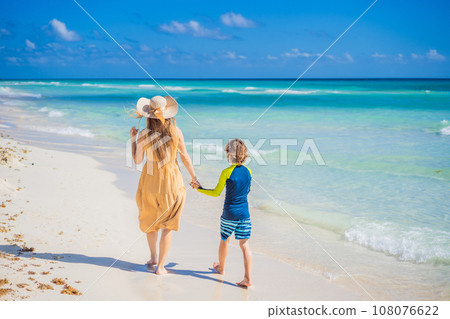 Family having fun and enjoying the white sandy beach on sunny day. Summer vacation for family in tropical paradise caribbean island coast, touristic destination for family vacations and leisure. GO 108076622