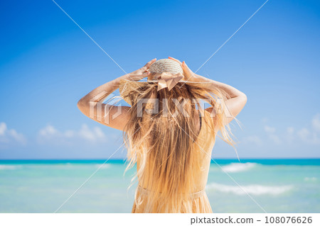 Happy traveller woman in yellow dress enjoys her tropical beach vacation. GO Everywhere 108076626