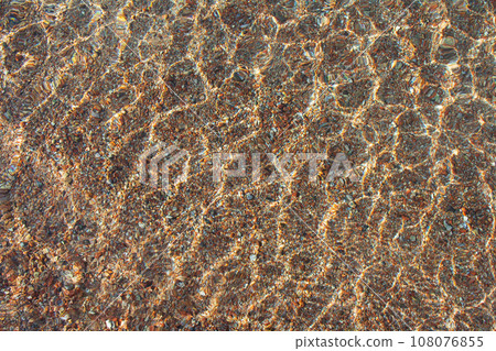 Transparent texture of sea, lake surface of clear water with ripples above sandy pebble bottom. Abstract summer background. Copy space Transparent texture of sea, lake surface of clear water with ripples above sandy pebble bottom. Abstract summer background. Copy space 108076855