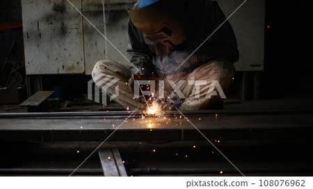 A man welding iron pipes 108076962