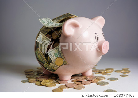 broken piggy bank. coins and banknotes fall out of piggy bank into holes. financial crisis, budget deficit, debt, bankruptcy. gray background 108077463