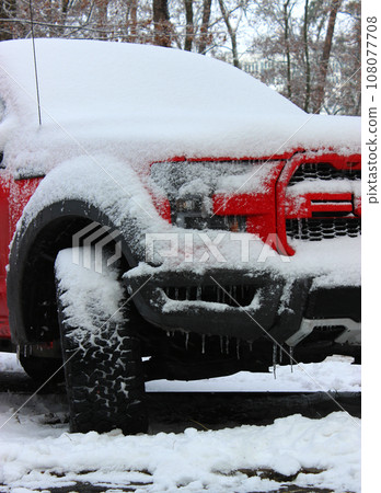 Front wheel, hood and windshield of a car covered with snow and hanging icicles Front wheel, hood and windshield of a car covered with snow and hanging icicles 108077708