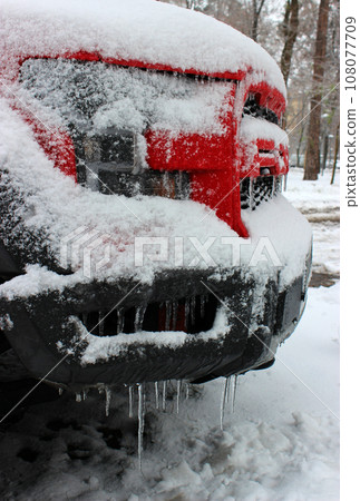 Icicles On A Front Bumper And Radiator Grill Of Car Covered With Snow Side View 108077709