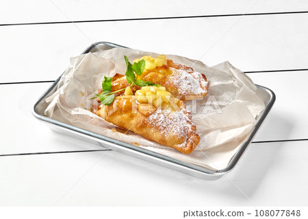 Puff pastry apple turnovers with powdered sugar and fresh mint 108077848
