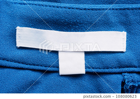 White blank laundry care clothes label on blue fabric background 108080623