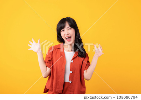 Portrait young beautiful asian woman happy smile dressed in orange clothes showing fist up hand gesture isolated on yellow studio background. Successful hooray celebrate young person concept. Portrait young beautiful asian woman happy smile dressed in orange clothes showing fist up hand gesture isolated on yellow studio background. Successful hooray celebrate young person concept. 108080794