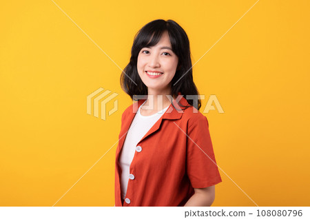 Portrait young beautiful asian woman happy smile dressed in orange clothes isolated on yellow studio background. Asian girl human face. 108080796