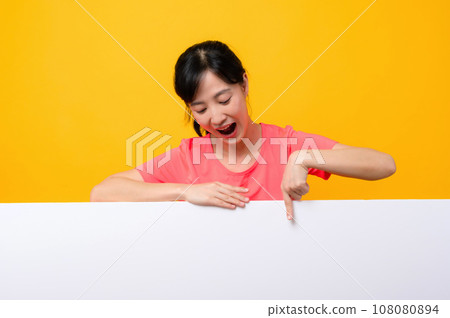 young asian sports fitness woman happy smile wearing pink sportswear standing behind the white blank banner or empty space advertisement board against yellow background. wellbeing lifestyle concept. young asian sports fitness woman happy smile wearing pink sportswear standing behind the white blank banner or empty space advertisement board against yellow background. wellbeing lifestyle concept. 108080894