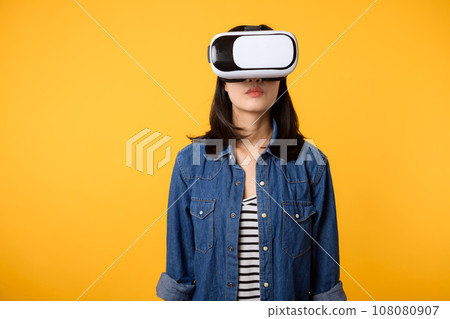 Young asian woman get experienced wearing virtual reality headset game entertainment isolated on yellow background. Winner of cyber future video game concept. 108080907