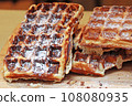 A lot of Freshly made belgian waffles sprinkled powdered sugar 108080935