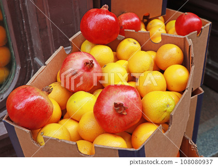 Oranges and pomegranates in a cardboard box at a street market Oranges and pomegranates in a cardboard box at a street market 108080937
