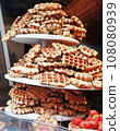 A lot of Freshly made belgian waffles sprinkled powdered sugar. 108080939