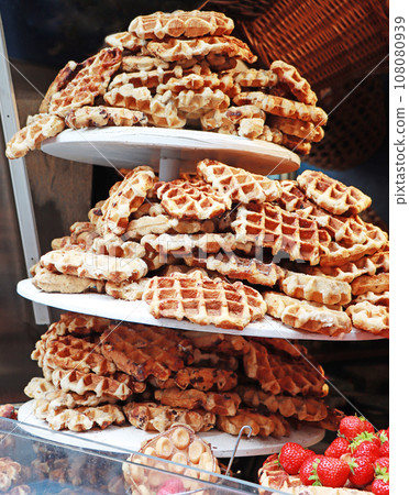A lot of Freshly made belgian waffles sprinkled powdered sugar. 108080939