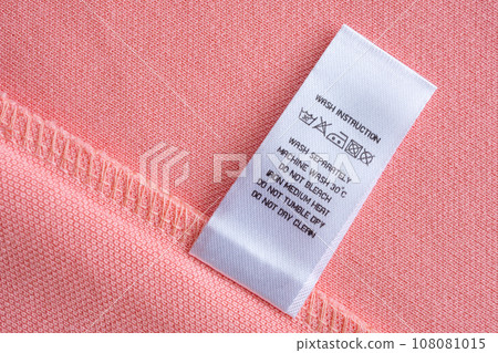 White laundry care washing instructions clothes label on pink cotton shirt 108081015