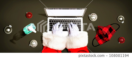 Santa Claus using a laptop computer with a mask and a sanitizer bottle Santa Claus using a laptop computer with a mask and a sanitizer bottle 108081194