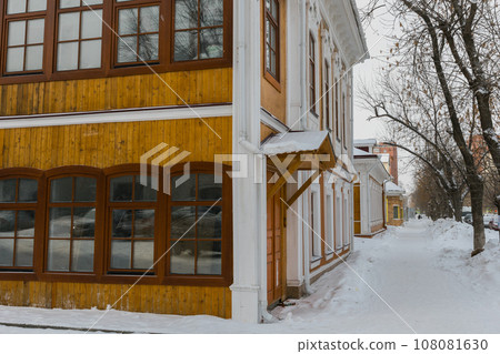 Exterior design of wooden red cottage in snowy town. Winter street with small buildings, cold season in city Exterior design of wooden red cottage in snowy town. Winter street with small buildings, cold season in city 108081630