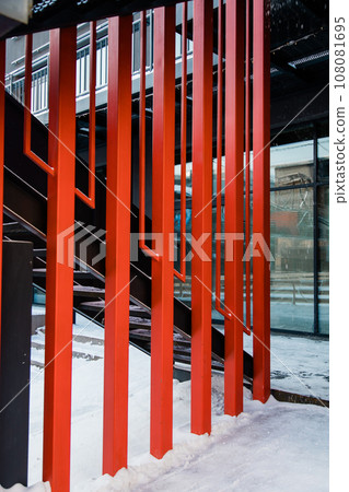 Fire escape ladder or emergency exit with steel staircase on wall of modern industrial building with red metal constructions 108081695