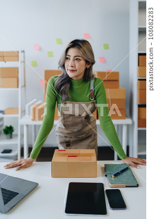 Starting small business entrepreneur of independent Asian woman smiling using computer laptop with cheerful success of online marketing package box items and SME delivery concept. Starting small business entrepreneur of independent Asian woman smiling using computer laptop with cheerful success of online marketing package box items and SME delivery concept. 108082283
