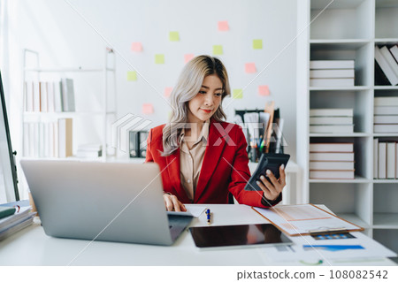 Beautiful young teen asian businesswoman using computer laptop and calculator for calculate with planning working on financial document, tax, exchange, accounting and Financial advisor. 108082542