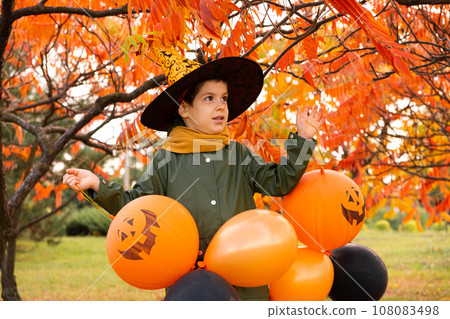 Happy Halloween kid playing with pumpkin balloons in park in autumn. Happy Halloween kid playing with pumpkin balloons in park in autumn. 108083498
