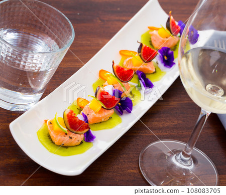 Ceviche from pickled red fish and cumquat a circle of kiwi, with figs at plate Ceviche from pickled red fish and cumquat a circle of kiwi, with figs at plate 108083705