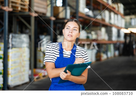 In warehouse of store, girl checks quantity of goods and receipt documents for products 108083710