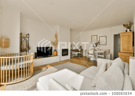 a living room with a baby cribt in the corner and an entertainment center on the wall is white a living room with a baby cribt in the corner and an entertainment center on the wall is white 108083834