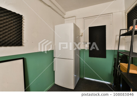 a green and white room with two refrigerators, one on the wall and another on the floor in the corner a green and white room with two refrigerators, one on the wall and another on the floor in the corner 108083846