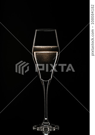 Backlit wine champagne glass with golden liquid white wine bubbles. Isolated black for holiday season New Year and Christmas Backlit wine champagne glass with golden liquid white wine bubbles. Isolated black for holiday season New Year and Christmas 108084182