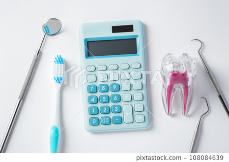 Dental tools with blue calculator and tooth on white background, top view Dental tools with blue calculator and tooth on white background, top view 108084639