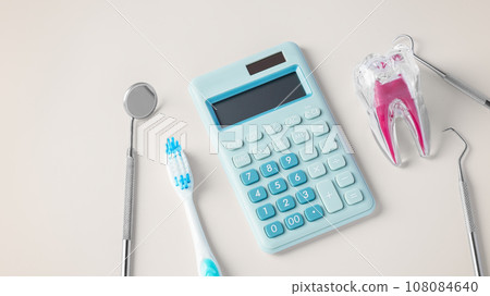 Dental cost concept with tooth, dentist tools and blue calculator on beige background Dental cost concept with tooth, dentist tools and blue calculator on beige background 108084640