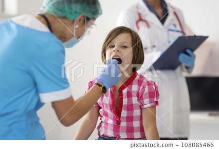 Doctor examines throat of little girl closeup 108085466