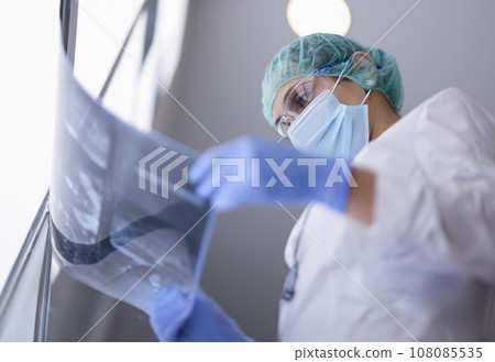 Doctor in protective medical mask looks at an X-ray. 108085535