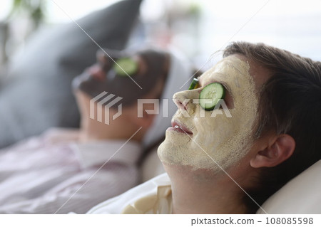 Cosmetic mask was applied to both male and female faces and cucumber slices on eyes. Cosmetic mask was applied to both male and female faces and cucumber slices on eyes. 108085598
