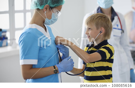 Boy in medical office listens to doctor's breath through stethoscope Boy in medical office listens to doctor's breath through stethoscope 108085616
