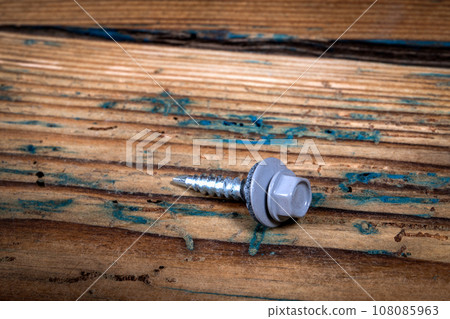 Roofing screw on a wooden texture background Roofing screw on a wooden texture background 108085963