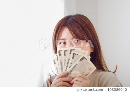 Young woman smiling and happily holding money Young woman smiling and happily holding money 108086040