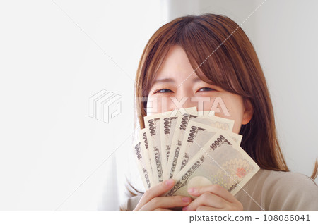 Young woman smiling and happily holding money Young woman smiling and happily holding money 108086041