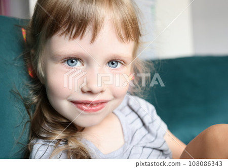 Portrait of little girl with blue eyes and slight smile 108086343