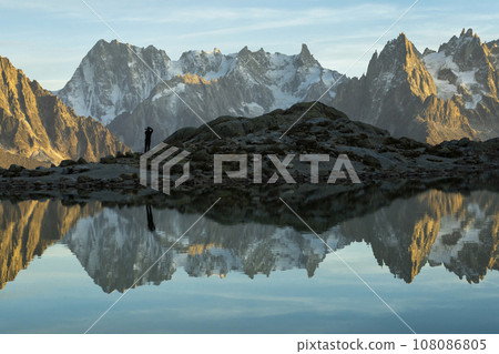 Photographer Man, Mountains and Reflection in Lac Blanc Lake at Sunset. Golden Hour. Chamonix 108086805