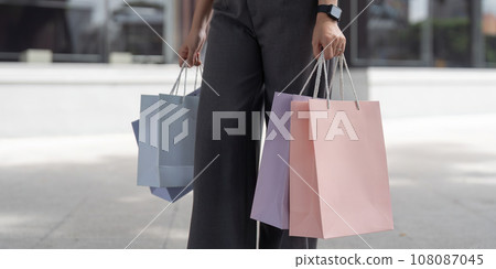 Happy beautiful young stylish woman with shopping bag while walking near mall on holiday Black Friday 108087045
