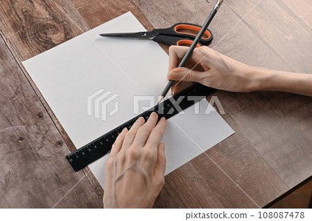 hands of an elderly woman fold origami paper. Creating an origami paper crane 108087478