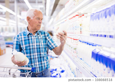 Old age man choosing milk in supermarket Old age man choosing milk in supermarket 108088518